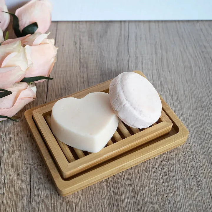 Hydrating shampoo and conditioner bar set on dual layer bamboo soap dish.