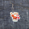 Top view of an Autumn Moose eco-friendly cellulose pop-up kitchen sponge with hanging cord, featuring a charming red moose beside a maple tree design - lying flat when dry and expanding when wet for seasonal cleaning with natural charm.