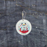 Top-down view of an eco-friendly cellulose pop-up kitchen sponge with hanging string, flat when dry and expands when wet, featuring a cute snowman donut design.