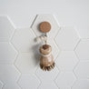 Wooden dish brush with a wooden handle on a white tiled wall