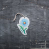 Top view of an eco-friendly cellulose pop-up kitchen sponge featuring a delightful blue daisy pattern, complete with hanging cord. This innovative cleaning tool lies completely flat when dry (just 0.3cm thin) for space-saving storage, then expands to a full 1.5cm thickness when wet for superior absorbency. Made from 100% biodegradable plant-based cellulose, the sponge combines sustainable functionality with charming floral aesthetics - the vibrant blue daisy design adding a cheerful touch to kitchen chores 