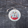 Top-down view of an eco-friendly cellulose pop-up kitchen sponge with hanging string, flat when dry and expands when wet, featuring a cute snowman donut design.