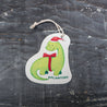 Top view of an eco-friendly cellulose pop-up kitchen sponge with hanging cord, featuring an adorable holiday dinosaur wearing a red Santa hat and red bow tie - lying flat when dry and expanding when wet for festive yet functional cleaning.