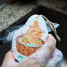 Eco-friendly pop-up sponge with capybara in hot bath design, oranges floating nearby. Expanded cellulose kitchen sponge covered in soap bubbles. Hand using biodegradable sponge on dish, demonstrating effective, sudsy cleaning. Playful, earth-friendly kitchen helper in action