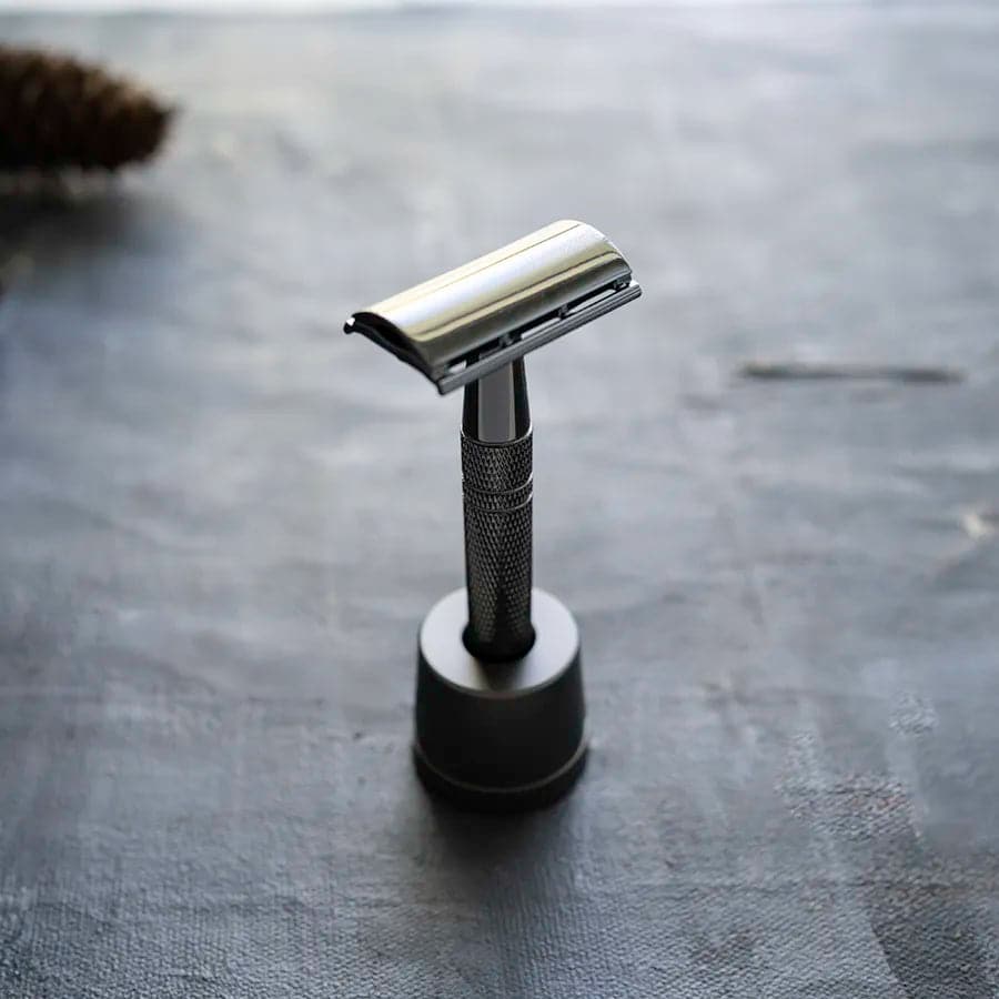 The Metallic Black Safety Razor Blade kit with stand offers a stylish and functional shaving solution. This sleek razor kit includes a metallic black safety razor and a stand, combining aesthetics with practicality for a superior shaving experience.