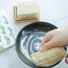 Using contemporary loofah sponge with solid dish soap brick for dishwashing, cleaning pan.