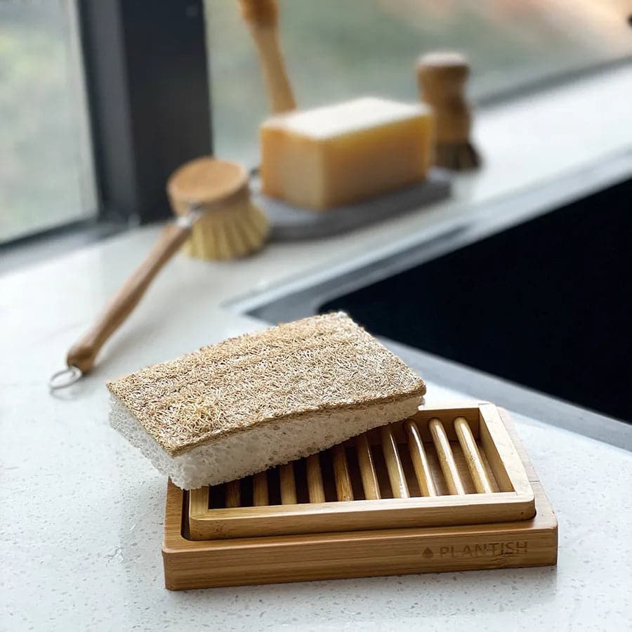 Loofah kitchen sponge on top of natural bamboo dual layer soap dish.