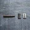 Disassembled double edged safety razor in metallic black with single blade.