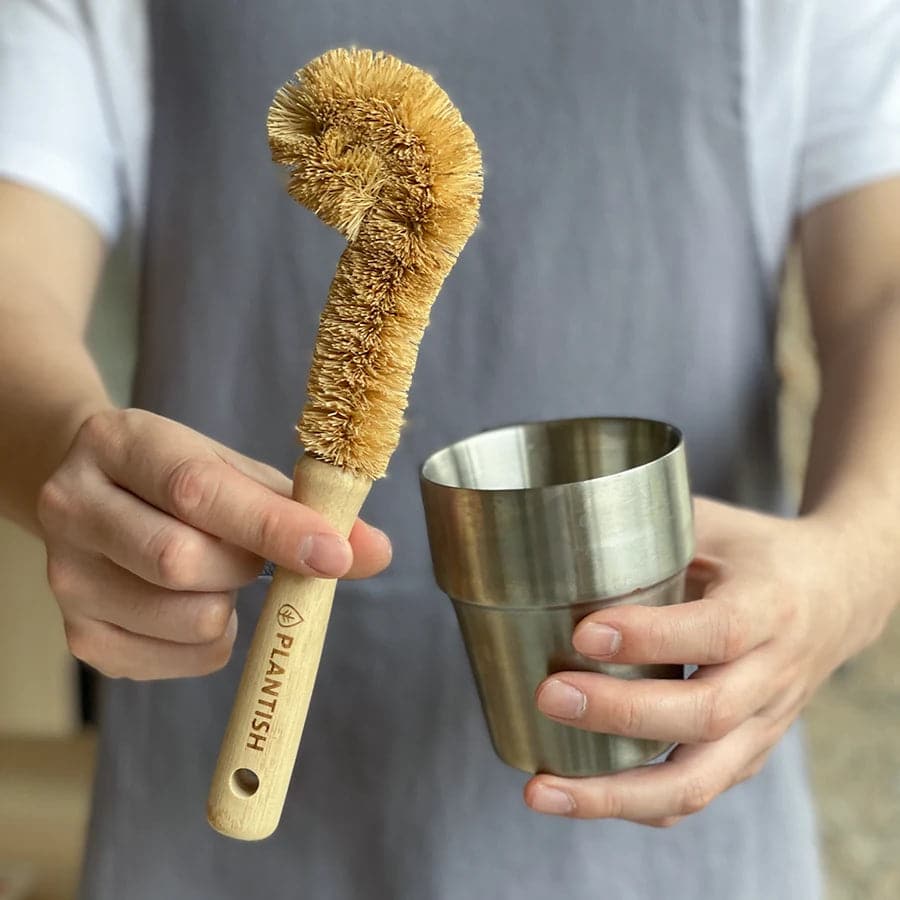 Plastic free coconut bottle brush size compared to cup. Great eco friendly alternative for kitchen cleaning needs.