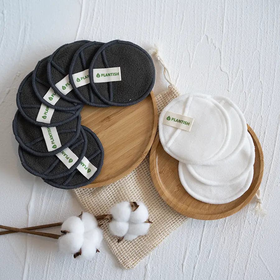 Organic cotton, reusable cotton rounds on top of circular natural bamboo soap dish and mini mesh bag.