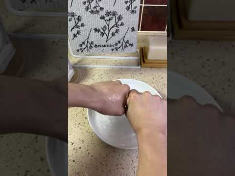 Video of hands wringing out water from reusable sponge cloth.