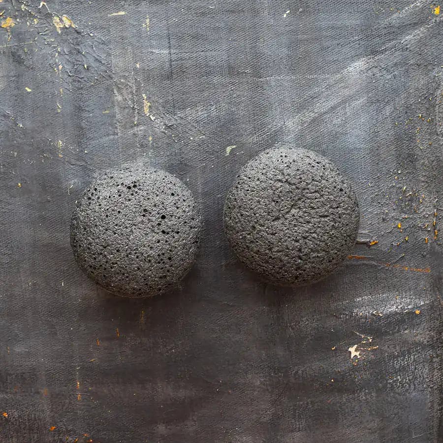 Two charcoal konjac facial sponges for exfoliating and cleansing the skin.