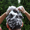 Lathering shampoo into hair to create generous foam.