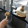 Using sisal dish brush to clean dishes. Sisal and palm pot scrubber on top of solid dish soap bar.